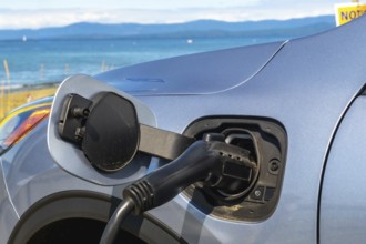 Electric car is being charged at a station by the sea, promoting eco friendly travel and