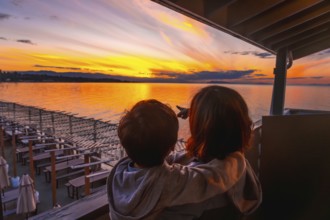 Mother and son bonding while enjoying breathtaking golden sunset view over qualicum beach on