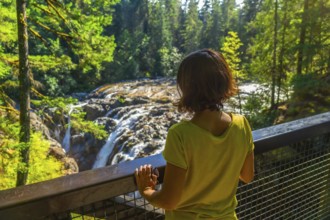 Female tourist standing on a viewpoint, admiring englishman river falls cascading through lush