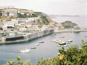 Historic waterfront buildings, boats at low tide in harbour at Mevagissey, Cornwall, England, UK, c