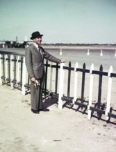Portrait of smartly dressed man wearing a suit and hat standing at an airport c 1956