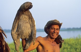 A man who runs a small private zoo near Iquitos on the Amazon shows a sloth, Peru, South America,