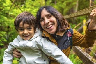 Mother and son are enjoying a hike in a lush rainforest, sharing a happy moment together surrounded