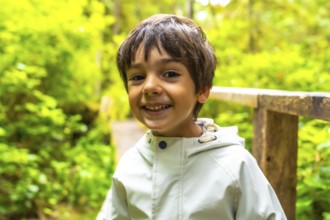 Young child smiles while exploring a lush rainforest trail in ucluelet, a town on vancouver island,