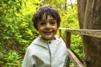 Happy child enjoying a walk in nature on a wooden boardwalk trail surrounded by lush green