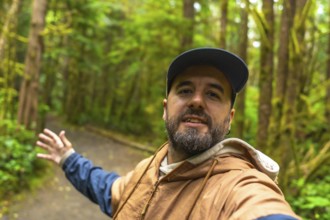 Tourist wearing casual clothing and a baseball cap is gesturing to the rainforest trail while
