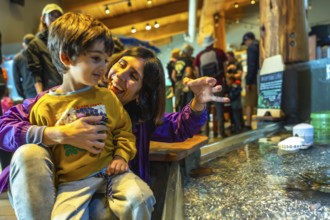 Mother and her son are enjoying a day at the aquarium, observing marine life in a touch tank,