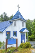White church building with a blue roof and accents, nestled in ucluelet, british columbia,