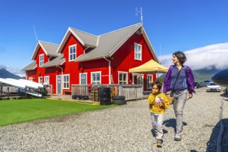 Tourists walking near a vibrant red building in tofino, a charming district on vancouver island's