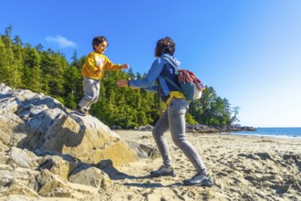 On a sunny summer day in tofino, british columbia, a mother extends her hands to help her child