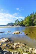 Crystal clear shallow inlet water reflects the vibrant summer sky, creating a picturesque scene in