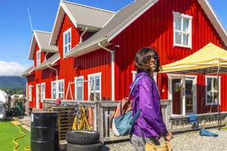 Female tourist walking near a red wooden building in tofino, a popular travel destination on