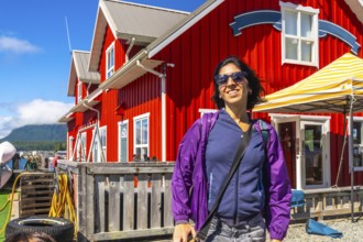 Happy tourist smiling in front of a characteristic red building in tofino, a popular travel
