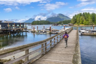 Tourist with backpack walking down a pier in tofino, british columbia on a beautiful summer day