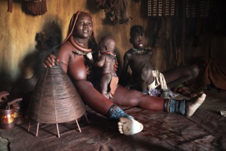 Himba woman sitting with baby, Himba perfume, scented smoke from burning plants, Himba village,