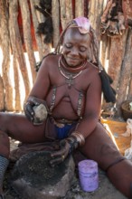 Himba woman grinding grain on a stone, Himba village, Kaokoveld, Kunene, Namibia