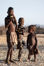 Three Himba children, traditional Himba village, Kaokoveld, Kunene, Namibia