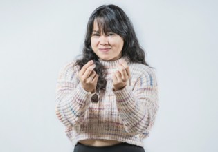 Cunning woman rubbing fingers showing money gesture isolated. Asian girl rubbing fingers asking for