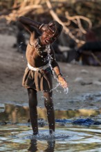 Himba child washing with water on a river, traditional Himba, Kaokoveld, Kunene, Namibia