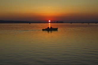 Sunset with boat in the middle of the lake, calm waters, peaceful view, Steinhude Steinhuder Meer