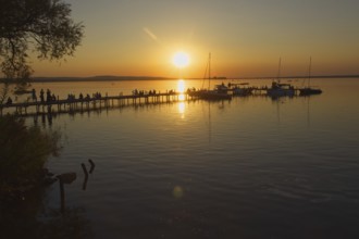 Sunset on Lake Steinhude with people on a jetty and sailboats, relaxed atmosphere, Steinhude