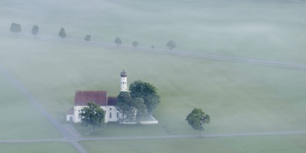 St. Coloman pilgrimage church in front of sunrise in autumn fog, Königswinkel, Ostallgäu, Allgäu,