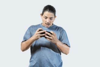 Surprised young man playing with cell phone isolated. Amazed gamer playing with cell phone isolated