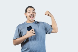Happy young man holding phone celebrating isolated. Winner guy celebrating with his phone isolated