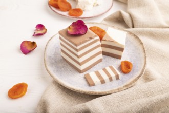 Cocoa and milk jelly with dried apricots on white wooden background and linen textile, side view,