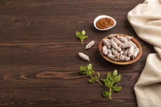 Small smoked Chicken sausages in wooden bowl on brown wooden background and linen textile. side