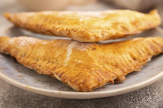 Triangles Pie, Puff Pastry, Samsa with cherry jam on brown concrete background and linen textile,