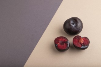 Purple Plum Cut in half on beige and gray pastel paper background. Side view, copy space. healthy