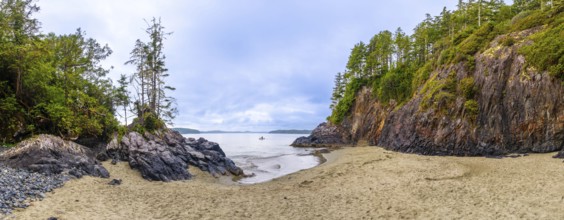 Panoramic view of a secluded beach and inlet in tofino, vancouver island, featuring dramatic rock