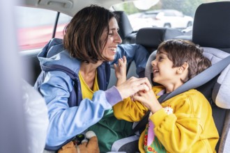 Mother turning back to her son, sitting in a child car seat, sharing joyful moments and laughter