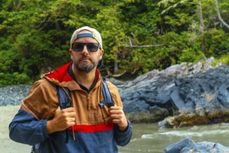 Male tourist wearing sunglasses and a baseball cap enjoying the stunning beaches of tofino, a