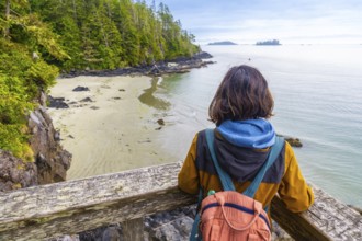 Tourist with a backpack is enjoying a breathtaking view of the ocean and coastline from a wooden