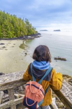 Tourist with a backpack is enjoying a breathtaking view of the ocean and coastline from a wooden
