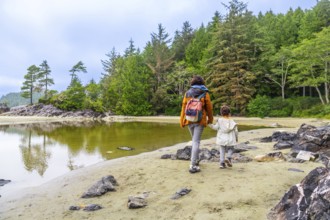 Mother and daughter, hand in hand, enjoy a peaceful stroll along mackenzie beach in tofino, british