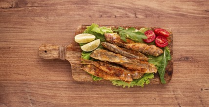 Fried crispy red mullet fish, on a wooden chopping board, with lime, no people