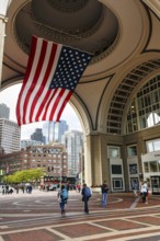 American flag fluttering, distinctive archway, Boston Harbor Hotel, Rowes Wharf, passers-by,