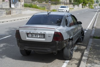 Grey Opel Vectra with modern rims and rear damage parked on the outskirts of the city, Armenia