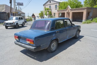 A blue car at an urban intersection on a clear sunny day, Lada 2107, also WAS-2107, VAZ-2107, Lada