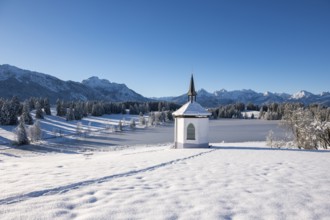 Idyllic chapel in snow with footprints in a picturesque winter landscape, Hegratsrieder See, near
