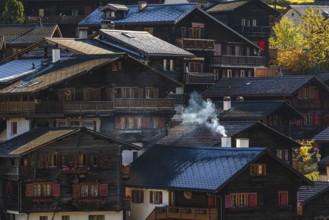 Smoke rises over the roofs of old wooden houses in Vissoie, Val d'Anniviers, Valais Alps, Canton of