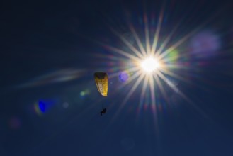 Paragliders against blue sky and bright sun, Val d'Anniviers, Valais Alps, Canton of Valais,