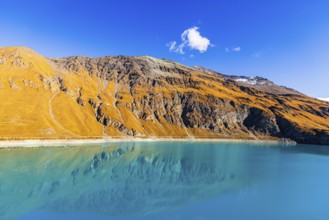 Steep and rocky mountain slopes are reflected in the La de Moiry Reservoir, Val d'Anniviers, Valais