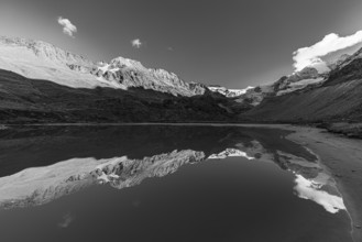 The Moiry glacier and mountain peaks are reflected in Lac de Chateaupre, black and white photo, Val