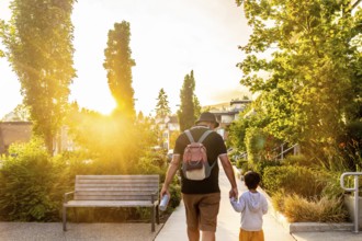 Father and son enjoying a leisurely stroll through a vancouver neighborhood at sunset, bathed in
