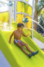 Happy child having fun sliding down a water slide at a colorful playground in kamloops, british