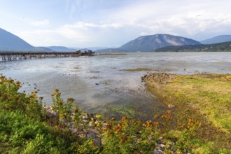 Shuswap lake reflecting a clear blue sky and framed by majestic mountains, featuring a charming
